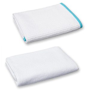 Two rectangular folded waffle-weave towel under each other. The top one has a light blue edge.