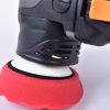 Close up of the rotating head of a corded black dual action polisher with a red foam pad.