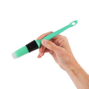 Detailing brush with mint and black handle and mint coloured bristles placed slightly diagonally on a hand.