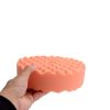 Orange polishing double sided waffle foam pad with a five eighths fitting being held by a hand.