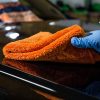 Close up of hand cleaning car bonnet with an orange plush microfiber cloth by Ewocar.